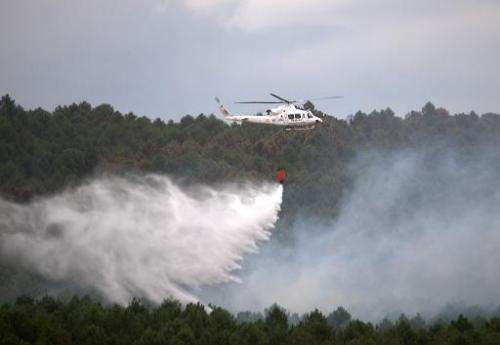 A firefighting helicopter drops water to extinguish a wildfire in Guadalajara, near Veguilla city, on July 19, 2014