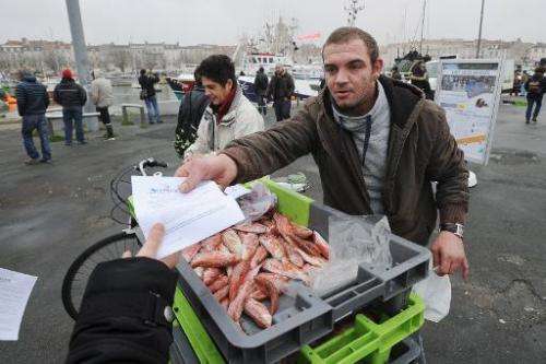 A fisherman distributes flyers during a protest against European Union fishing quotas on December 2, 2014, at La Rochelle harbor