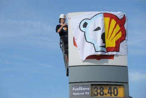 A Greenpeace activist half covers the Shell logo at a petrol station in Prague on May 10, 2012