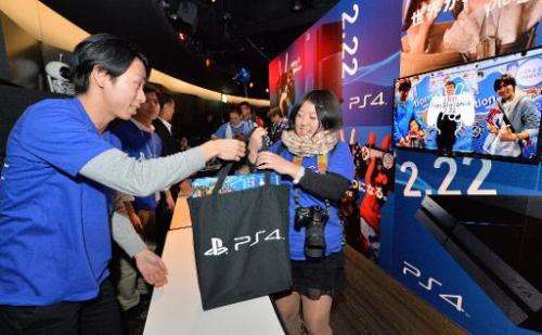 A Japanese customer (R) receives a Sony PlayStation 4 video game console following a countdown ceremony at the Sony building in 