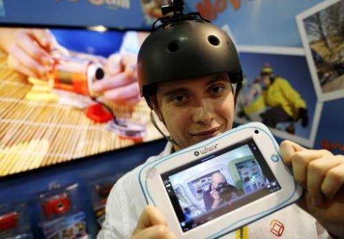 Alexandra Delage from Lexibook holds a tablet connected wirelessly to a mini camera attached to a helmet during the Toy Fair at 