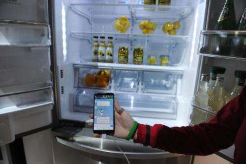 A LG representative shows a smartphone with Home Chat in front of a LG smart refrigerator at the 2014 International CES, January