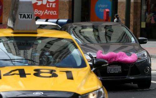 A Lyft car drives next to a taxi on June 12, 2014 in San Francisco, California