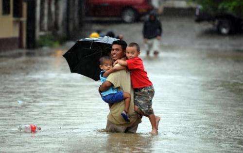 A man carries three children in a street flooded by the overflowing of Honduras' largest river, the Ulua, in El Progreso municip