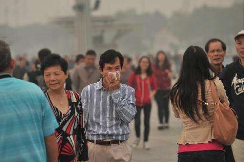A man covers his face as he walks on a street in Beijing amid heavy smog on October 9, 2014