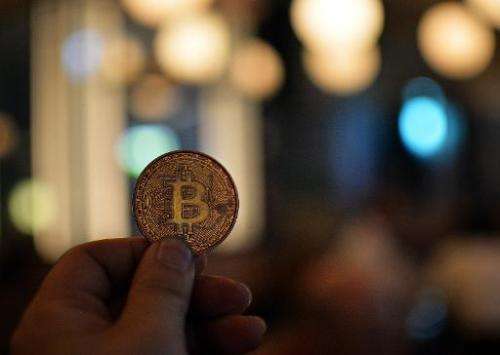 A man holds a bitcoin medal as members of bitcoin trading club hold a meeting in Tokyo on February 27, 2014