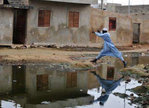A man jumps over a pond of stagnant water in the suburbs of Dakar on October 9, 2008