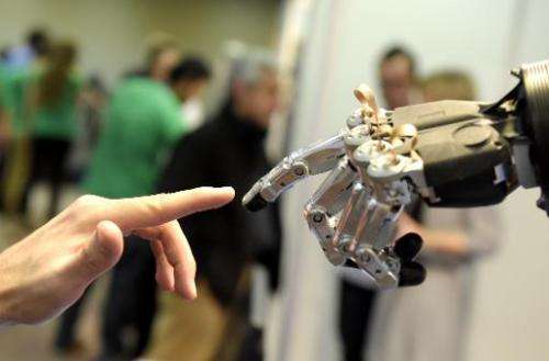 A man moves his finger toward an SVH automated hand made by Schunk during the 2014 IEEE-RAS International Conference on Humanoid