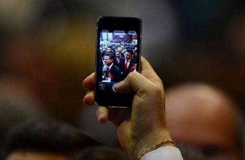 A man shows a picture on his phone of Mexican President Enrique Pena Nieto as he arrives for his inauguration ceremony at the Co