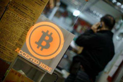 A man talks on a mobile phone in a shop displaying a bitcoin sign in Hong Kong on February 28, 2014