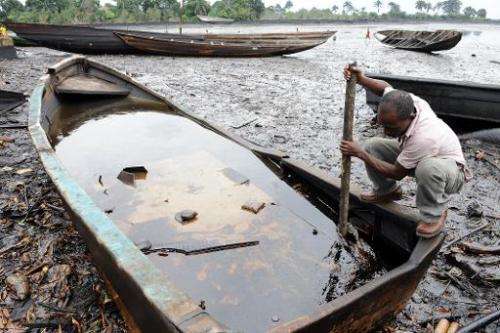 A man tries to separate crude oil from water in a boat at the Bodo waterways polluted by oil spills attributed to Shell equipmen