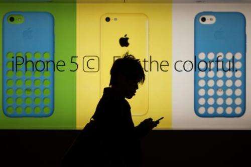A man uses his phone as he walks past an Apple store in Hong Kong on December 25, 2013