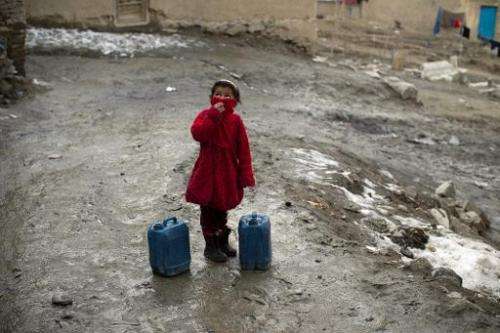 An Afghan girl takes a break from carrying water containers up a steep hill in Kabul on February 23, 2014