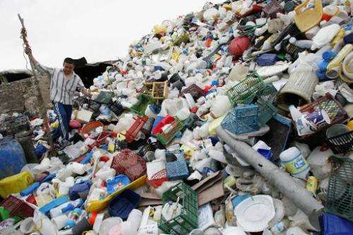 An Afghan migrant worker in Qaleh Sheikh village south of Tehran on May 3, 2007 walks over a mound of waste plastic produced by 
