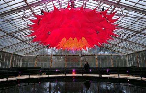 An employee poses behind a giant Lotus Flower installation in the Water Lilly House at Kew Royal Botanical Gardens in south west