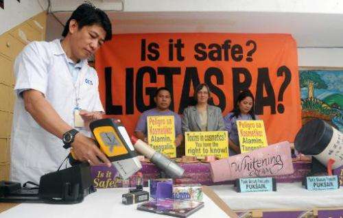 An engineer (L) from the EcoWaste Coalition checks cosmetics products for lead content in Manila on March 14, 2012