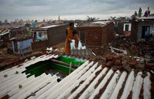 An Indian fisherman's wife prepares to fix a roof damaged in cyclone Phailin at Nalianuagaon in Ganjam district of Odisha in Oct