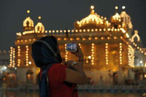 An Indian Sikh devotee takes a photograph on her mobile phone in the front of the illuminated Sikhism's holiest shrine, the Gold