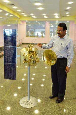 An Indian Space Research Organisation official uses a scale model of the Mars Orbiter Mission spacecraft to explain how parts of