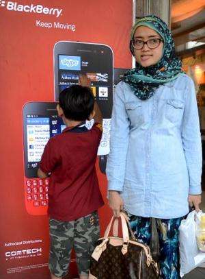An Indonesian woman and her son stand next to a Blackberry advertisement board at a shopping mall in Jakarta, May 10, 2014