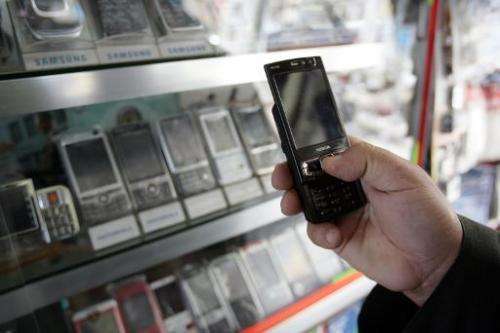 An Iraqi man checks a mobile phone at a shop in Baghdad on March 17, 2008