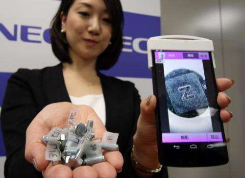 An NEC employee in Tokyo on November 10, 2014 displays fake products detectable with its new smartphone system