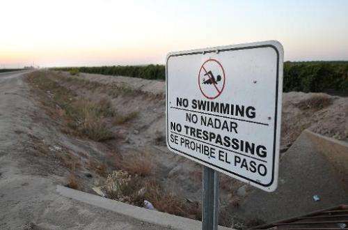 A no swimming sign is posted next to a dry irrigation canal on August 22, 2014 in Madera, California as a severe drought continu