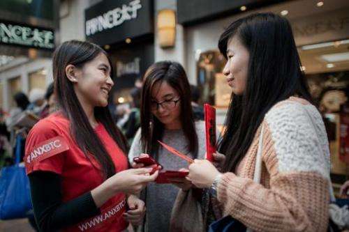A public relations woman (left) distributes lai see packets filled with bitcoin coupons to pedestrians to mark the Chinese New Y