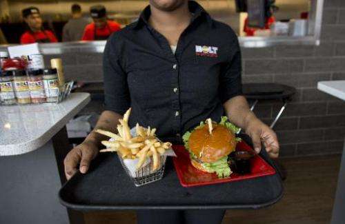 A server carries a tray with a hamburger and french fries at Bolt Burgers in Washington, DC, February 25, 2014