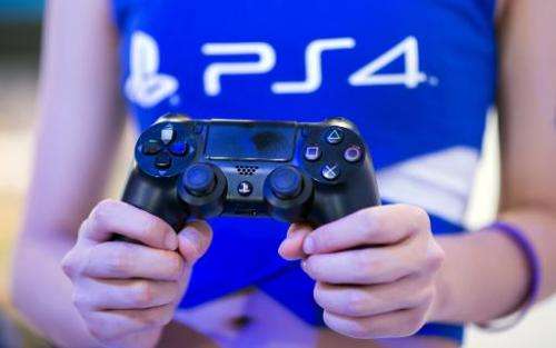 A Sony hostess holds the remote controls of a PlayStation 4 at the China Joy digital entertainment fair in Shanghai on July 31, 