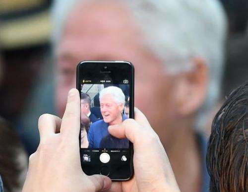 A supporter takes photos of former U.S. President Bill Clinton on a cell phone during a get-out-the-vote rally on October 28, 20