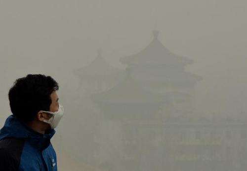 A tourist wearing a face mask climbs Jingshan Hill beside the Forbidden City as heavy air pollution shrouds Beijing