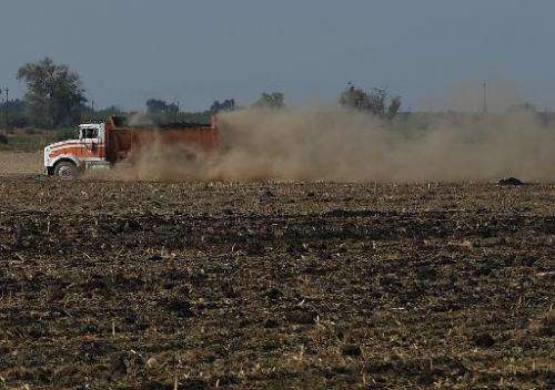 A vehicle raises a large dust cloud as it drives on a parched farm field in Los Banos, California on September 23, 2014