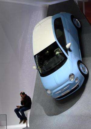A visitor sits next to a Fiat 500 displayed at the Italian carmaker's booth during the press day of the Geneva Motor Show in Gen