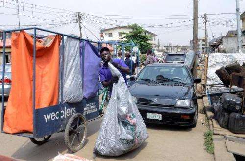 A 'Wecycler' worker collects recyclable goods from customers in Surulere district of Lagos, on January 17, 2014