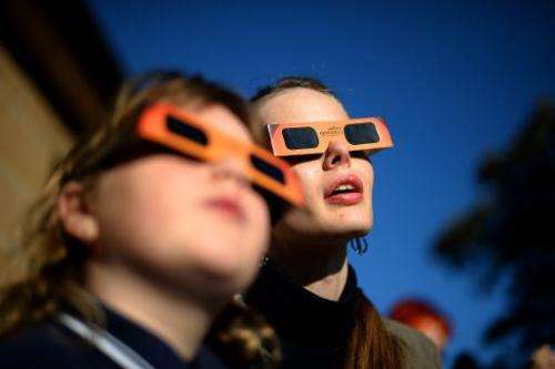 A woman (C) reacts while watching a partial solar eclipse with a child at the Sydney Observatory on May 10, 2013