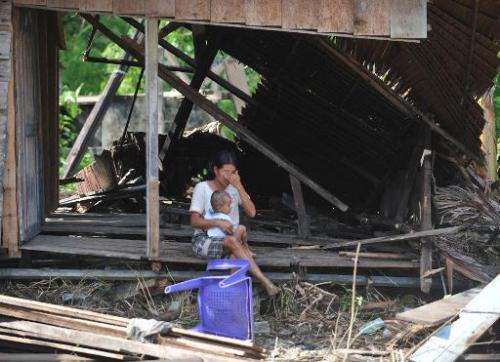 A woman sits with her daughter in her collapsed house on October 31, 2010 in Tumalei village, Metawai islands, Indonesia, six da