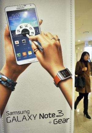 A woman walks past a sign board advertising Samsung Electronics' Galaxy Note 3 smartphone in Seoul on January 7, 2014