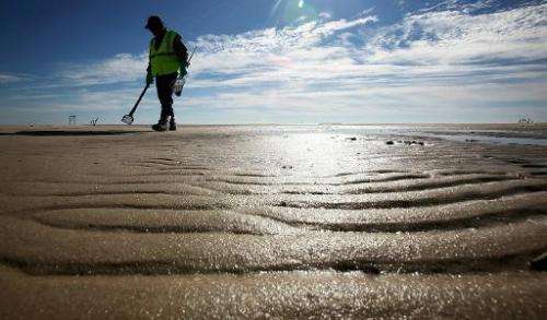 A worker cleans tarballs from the BP oil spill on Waveland beach December 6, 2010 in Waveland, Mississippi