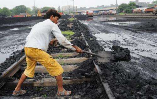 A worker lifts coal from a railway track to be transported to a truck at a railway yard in Ahmedabad in July 2013. India cancell