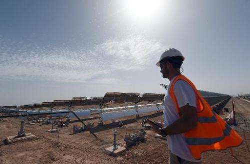 A worker stands in front of a solar array that is part of the Noor 1 solar power  project in Ouarzazate on October 19, 2014