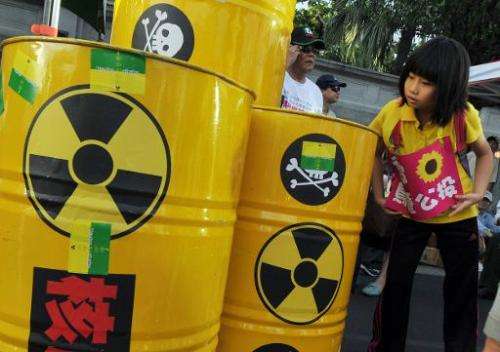 A young protester looks at hazardous waste barrels on display at an anti-nuclear demonstration in Taipei on May 19, 2013
