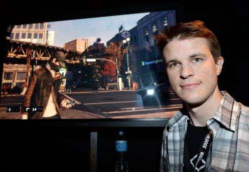 Canadian Ubisoft developer Dominic Guay next to a screen shot from the Ubisoft game &quot;Watch Dogs&quot; at the E3 video game 