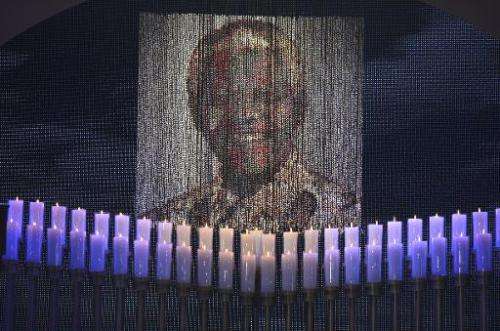 Candles are lit under a portrait of Neslon Mandela before the funeral of the former South African president in Qunu on December 