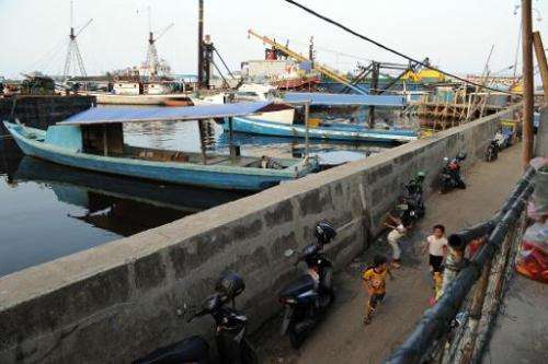 Children residing in the slum area play along a dyke as construction of the Jakarta sea wall begins, October 9, 2014