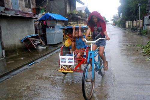 Children ride on a pedicab as it rains in Dolores town, eastern Samar, central Philippines on December 6, 2014