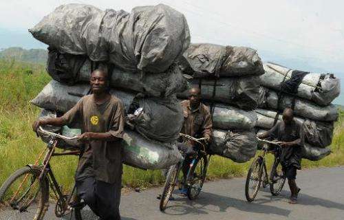 Congolese charcoal dealers push their bicycles up the hill as they transport their produce to the market in Sake, North Kivu, on