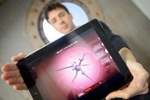 Creator James Vaughan holds a tablet device showing a screen from the video game &quot;Plague Inc&quot; in the company's London 
