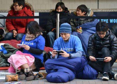 Customers queue outside the Sony building in Tokyo's Ginza shopping district on February 21, 2014 to get numbered tickets to pur