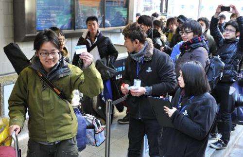 Customers receive numbered tickets outside the Sony building in Tokyo's Ginza shopping district on February 21, 2014 to purchase